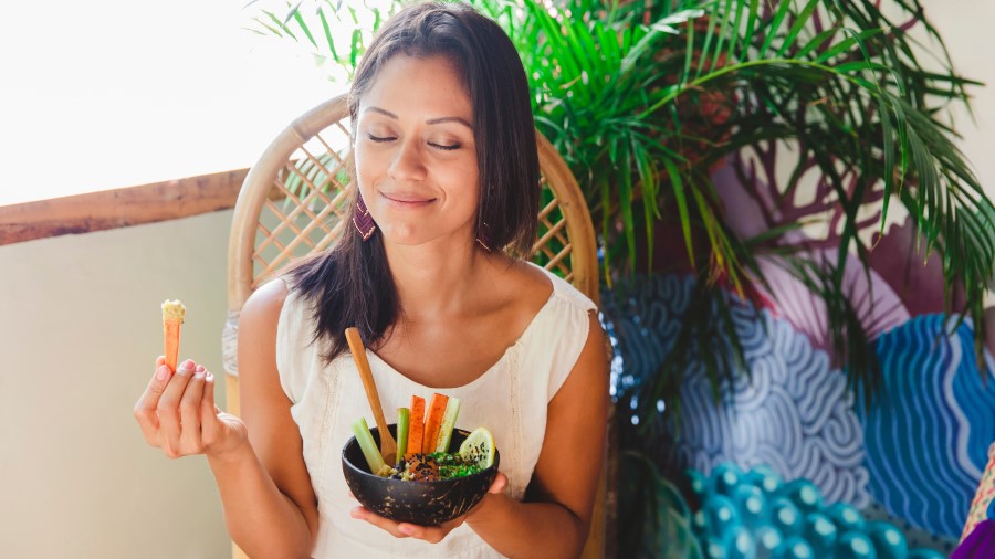 woman with eyes closed eating vegetables