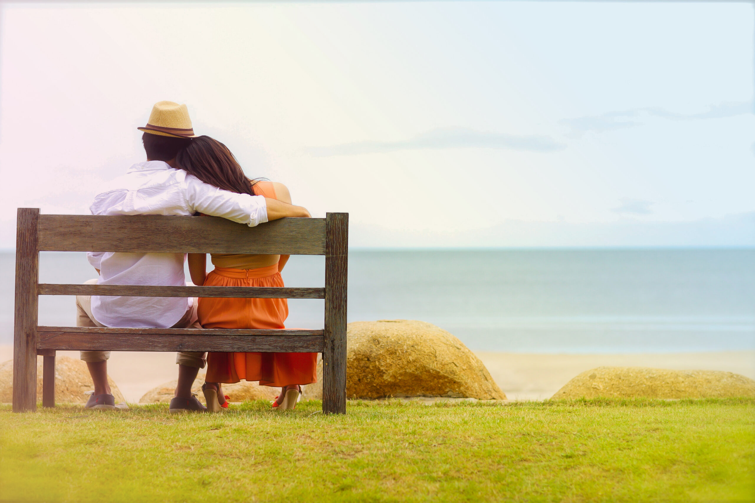 couple sitting on bench looking out to the ocean
